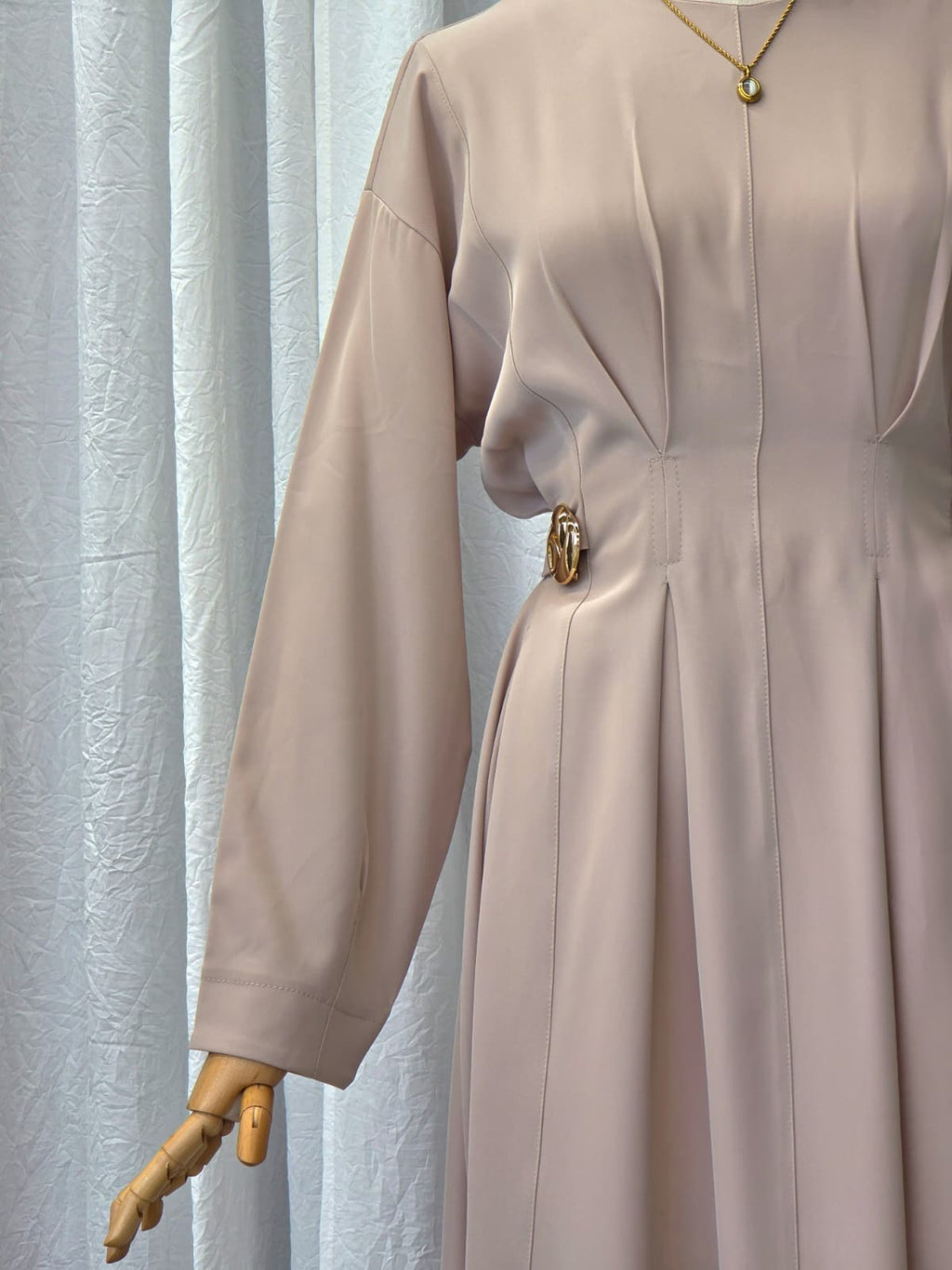Beige dress on a mannequin against a light curtain background