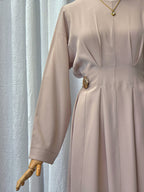 Beige dress on a mannequin against a light curtain background