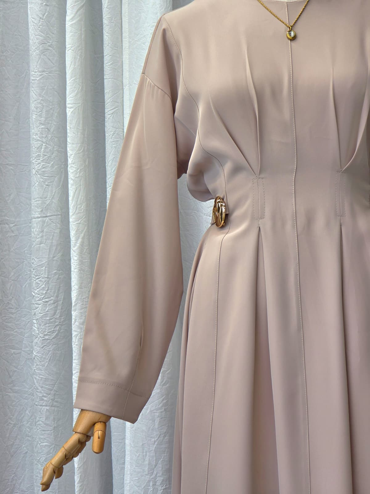 Beige dress on a mannequin against a light curtain background