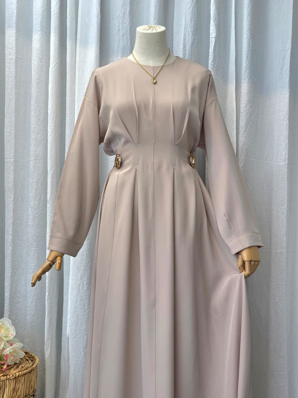 Beige dress on a mannequin against a light curtain background