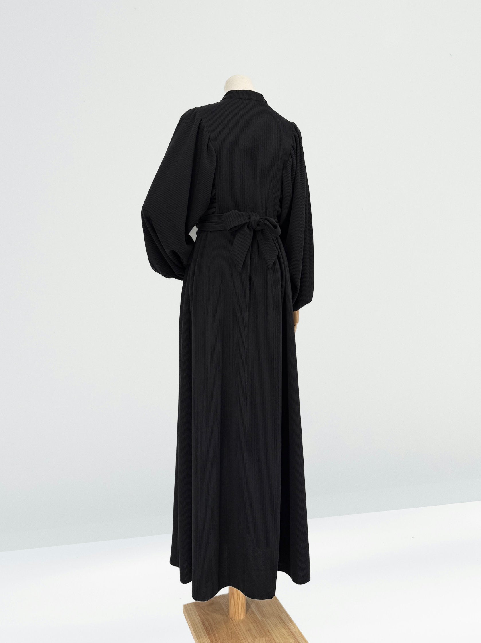 Black ribbed knit dress on a mannequin against a white background