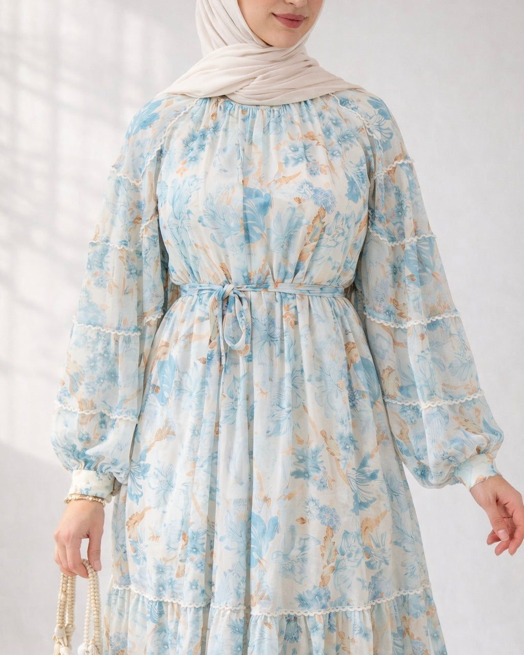 Woman wearing a blue floral dress with long sleeves on a white background