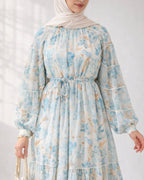 Woman wearing a blue floral dress with long sleeves on a white background