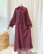 Burgundy dress with ruffled sleeves on a mannequin against a white curtain background