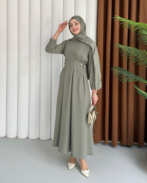 Woman wearing a long green dress with a matching hijab