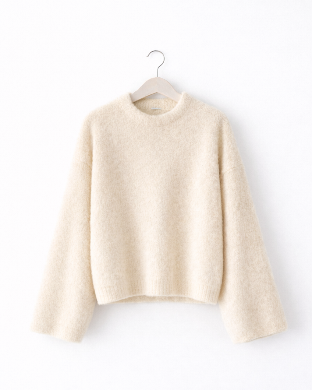 Beige sweater on a hanger against a white background