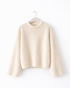 Beige sweater on a hanger against a white background