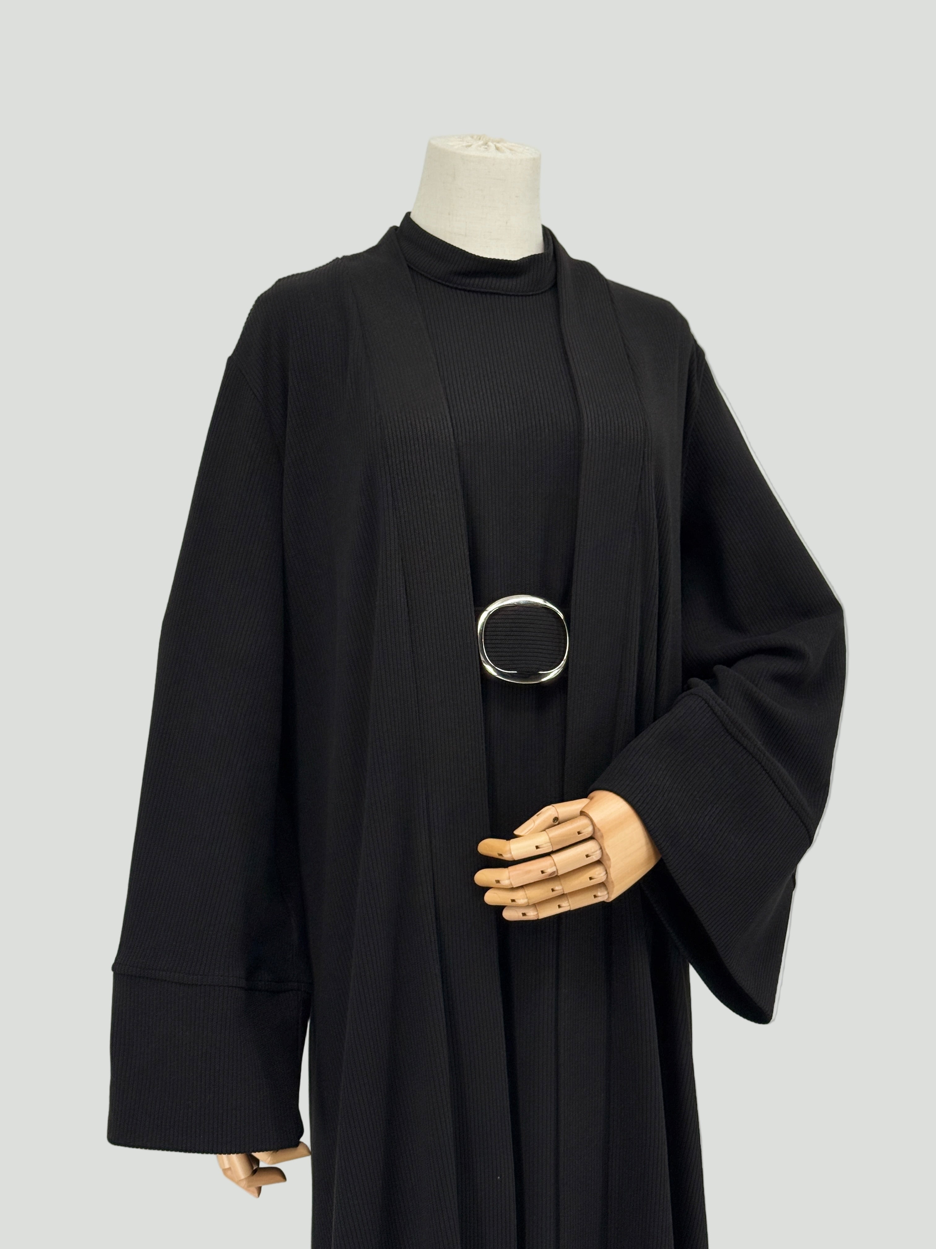 black abaya dress with a silver belt on a mannequin against a white background