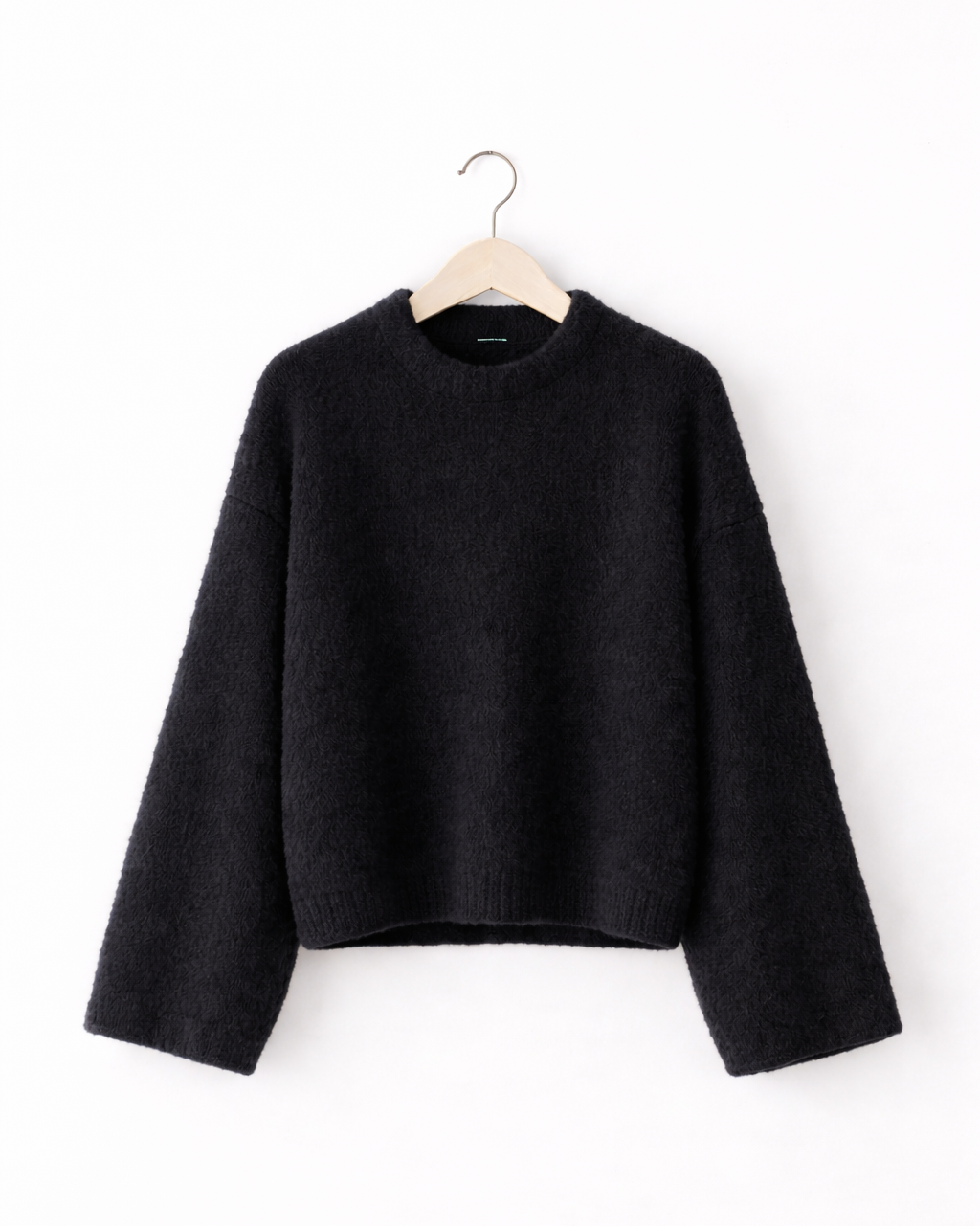 Black sweater on a hanger against a white background