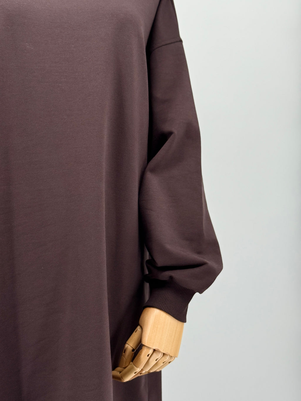 close-up of a brown long-sleeve tunic on a mannequin against a white background