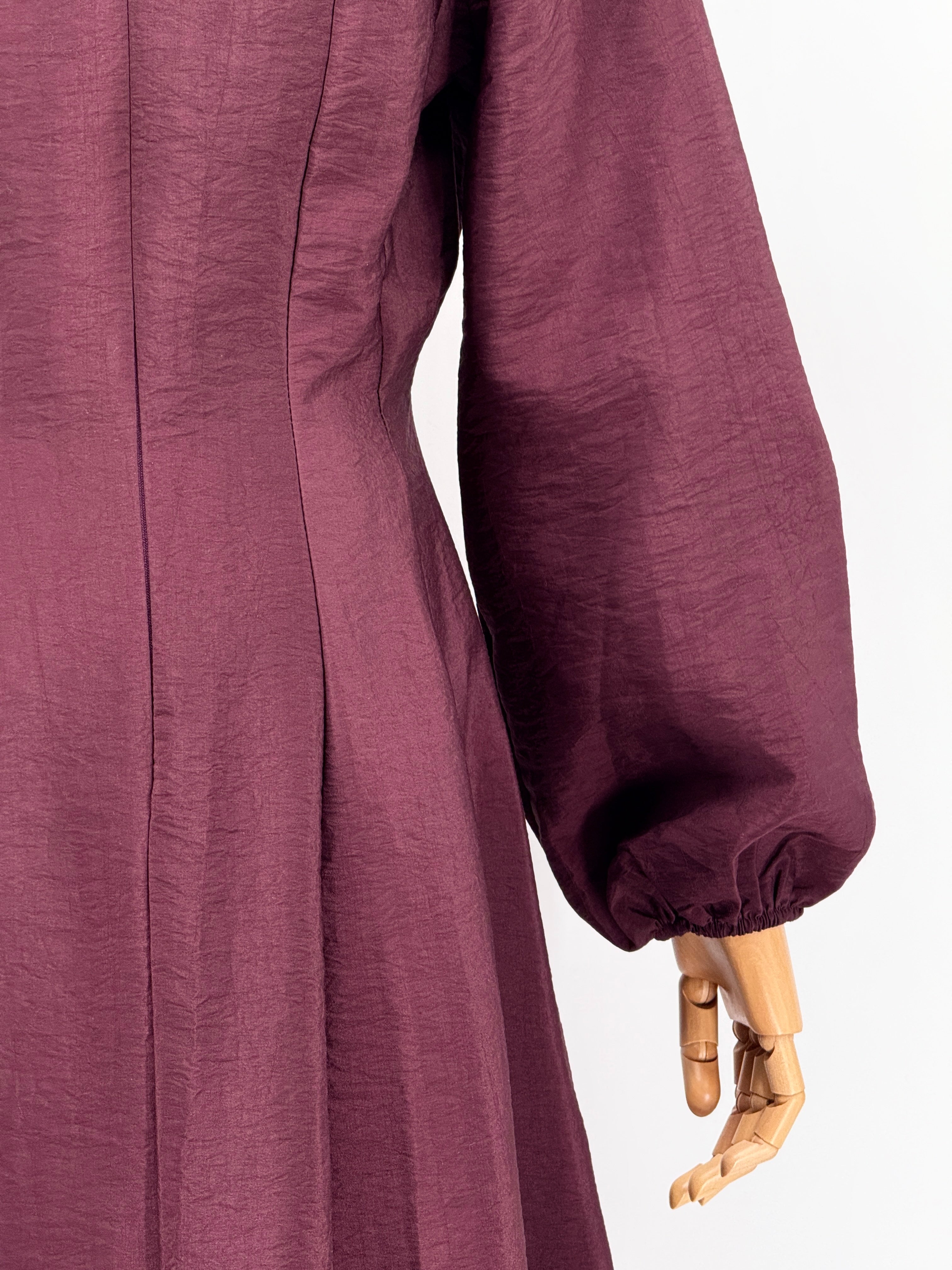 close-up of a burgundy flare dress on a mannequin against a plain background