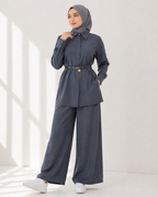 Woman wearing a blue gray outfit with a hijab on a white background