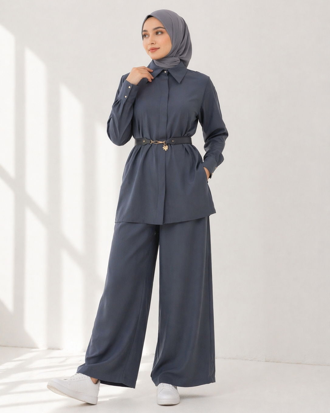 Woman wearing a blue gray outfit with a hijab on a white background