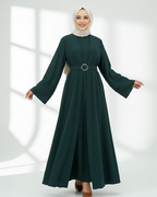 Woman wearing a dark green abaya dress with long sleeves on a white background
