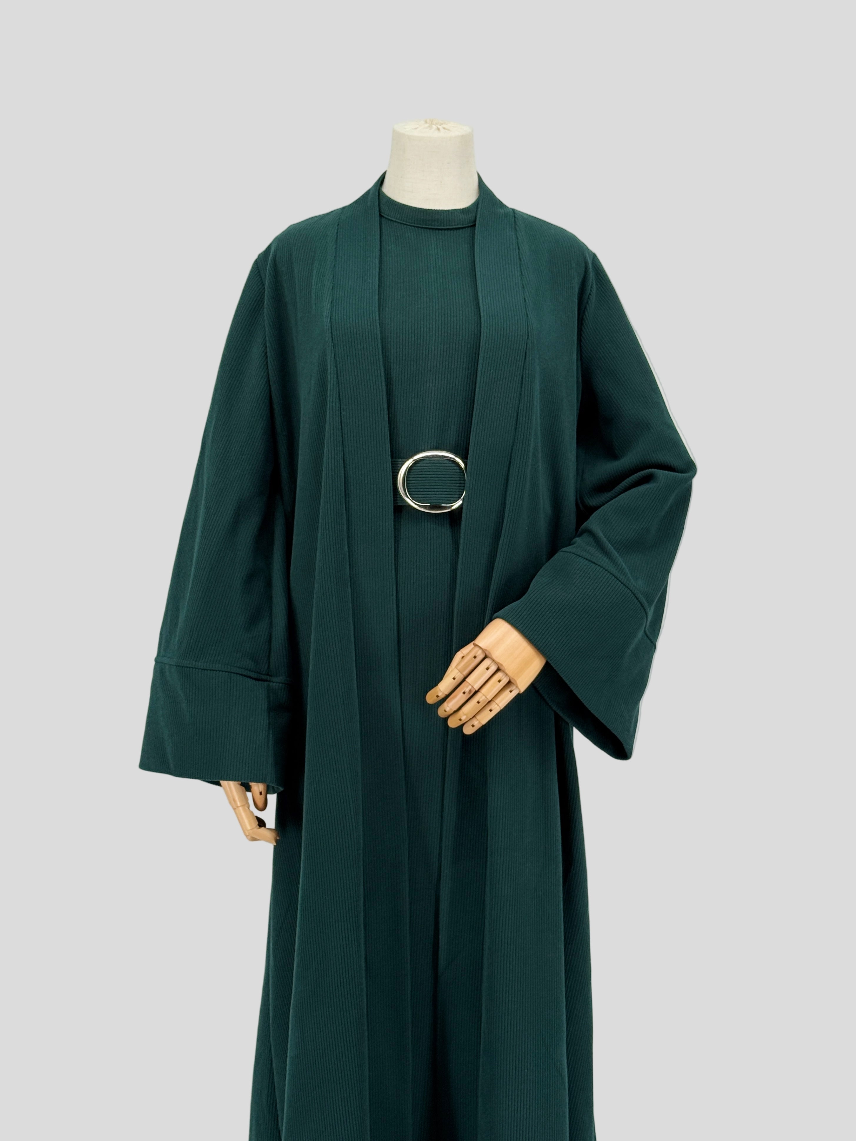 Dark green abaya on a mannequin against a plain background