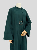 Dark green abaya on a mannequin against a plain background