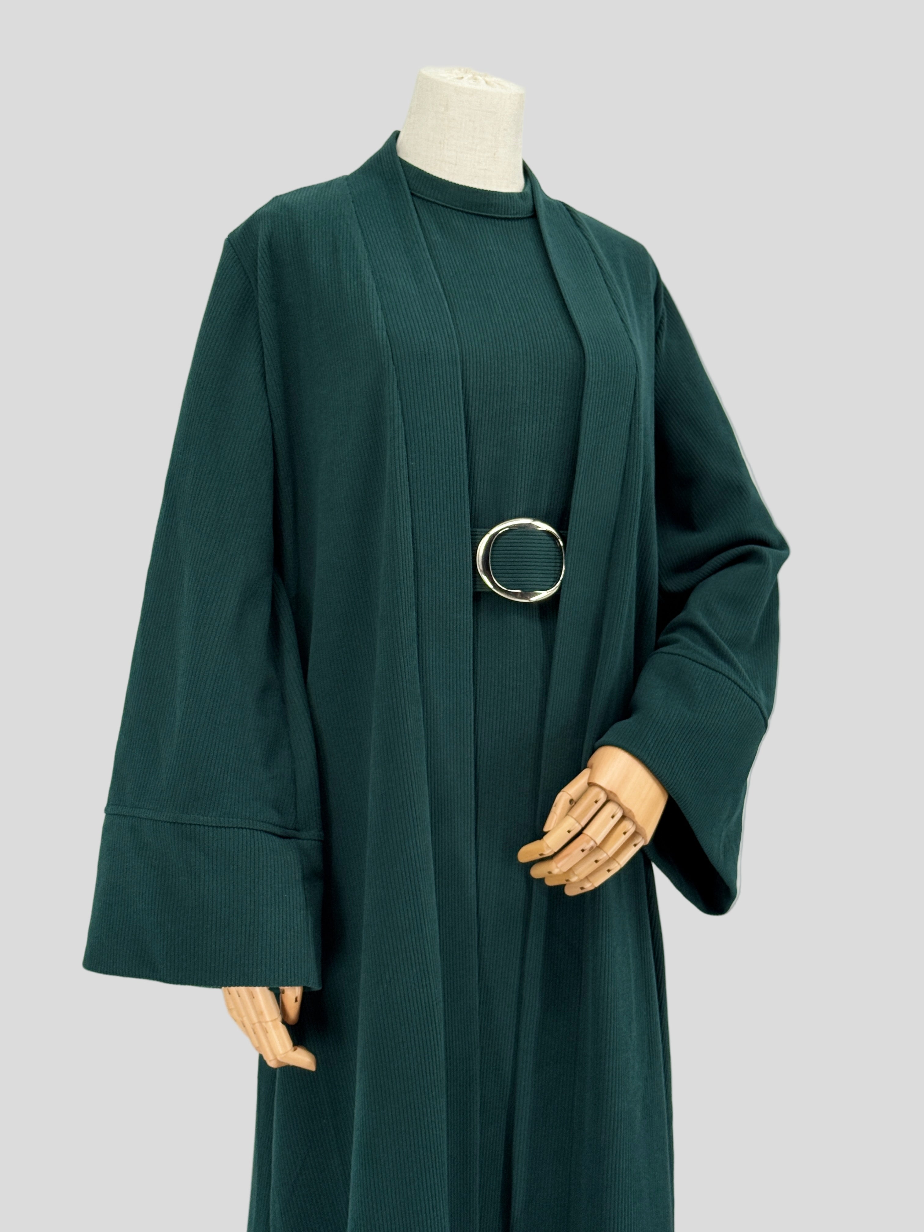 Dark green abaya on a mannequin against a plain background