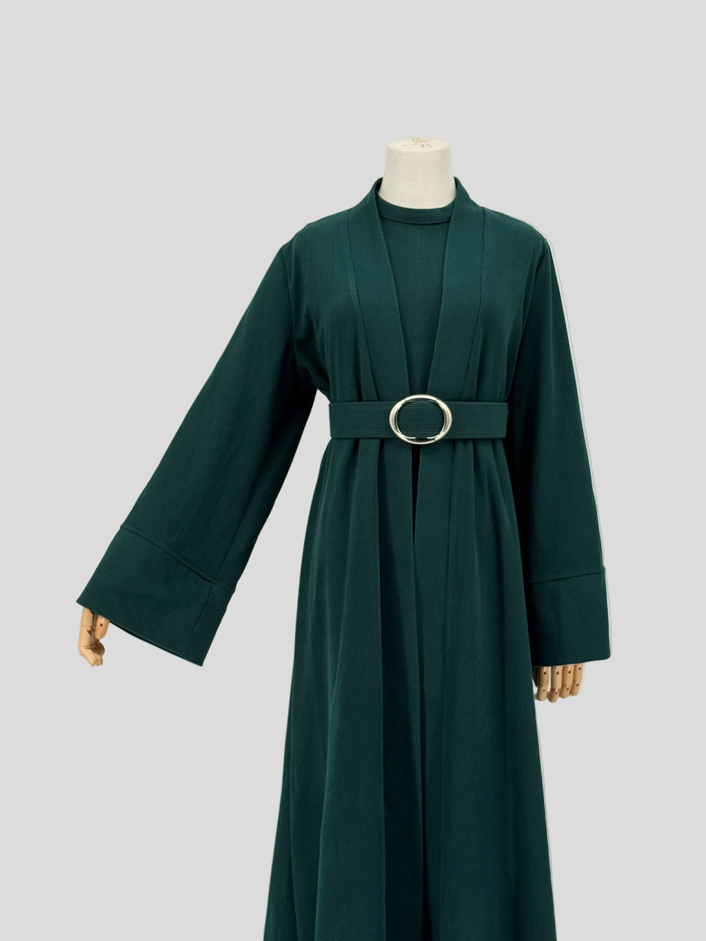 Dark green abaya on a mannequin against a plain background