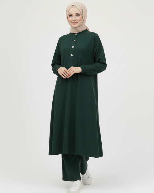 Woman wearing a dark green ribbed set with buttons on a white background