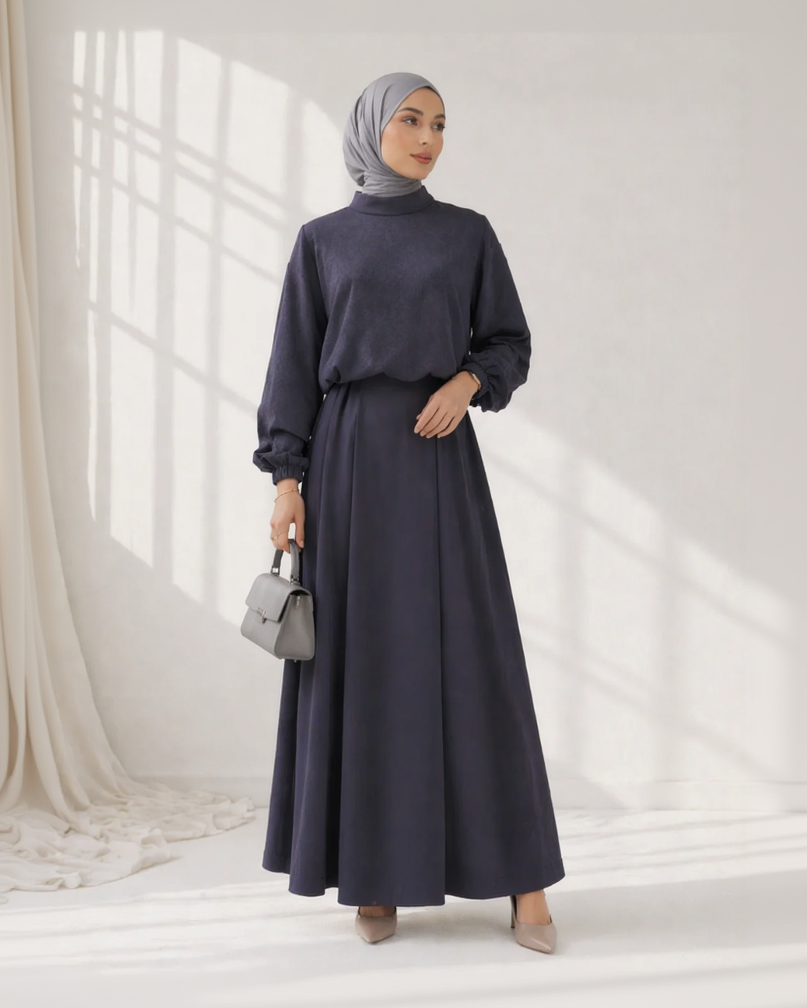 Woman wearing a navy blue outfit with a hijab in a bright room.