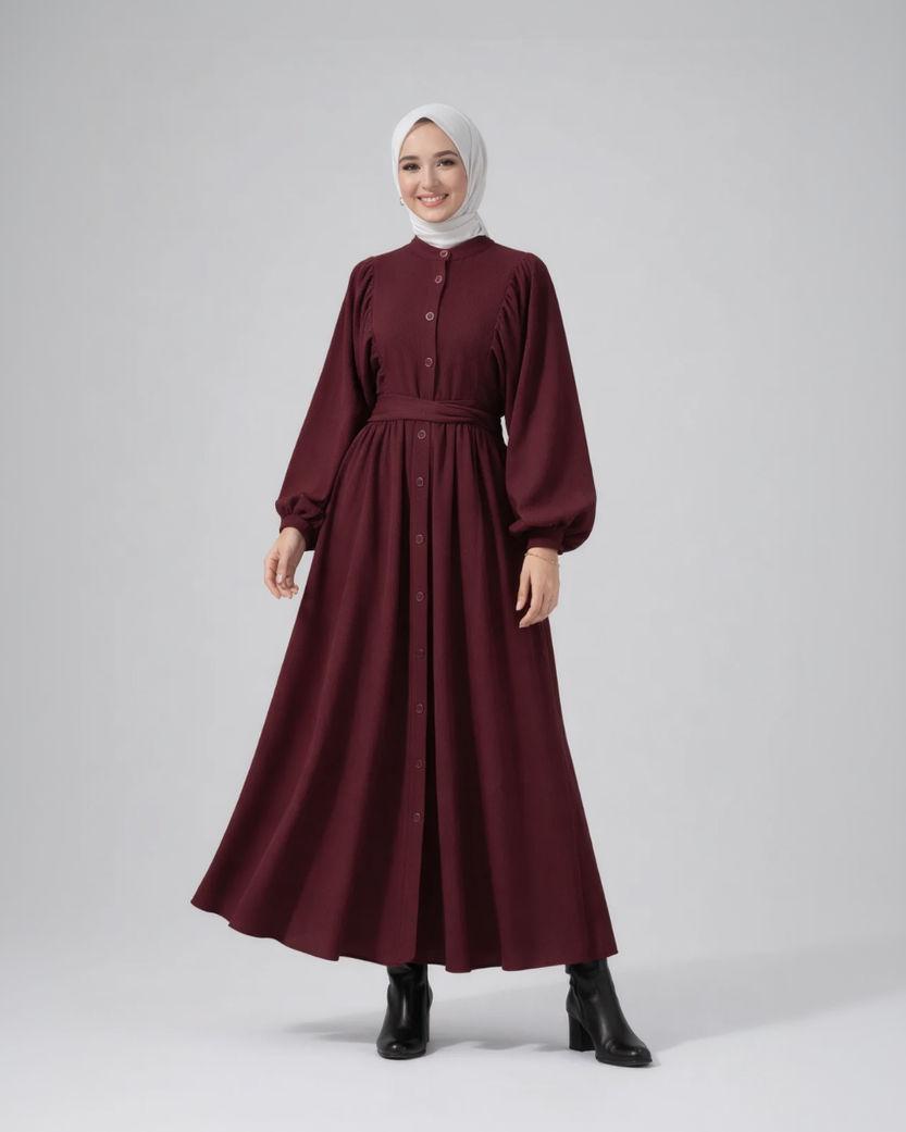Woman wearing a burgundy dress with a white hijab on a gray background