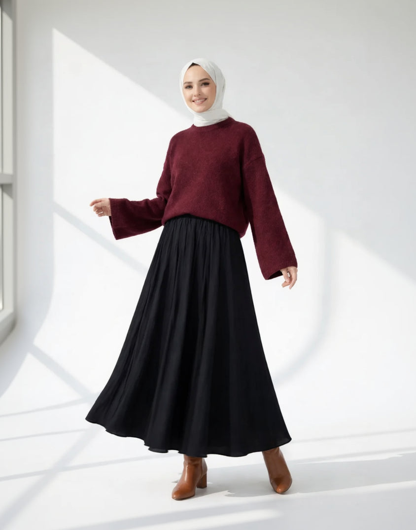 Woman wearing a burgundy sweater and black skirt on a white background