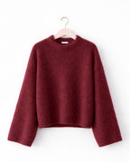 Maroon sweater on a hanger against a white background