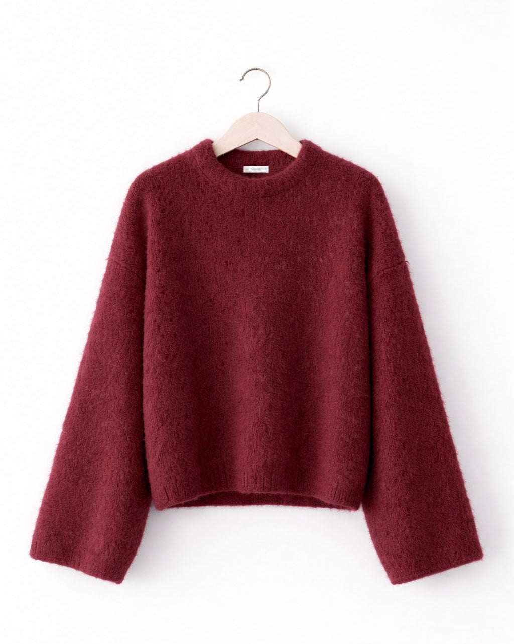 Maroon sweater on a hanger against a white background