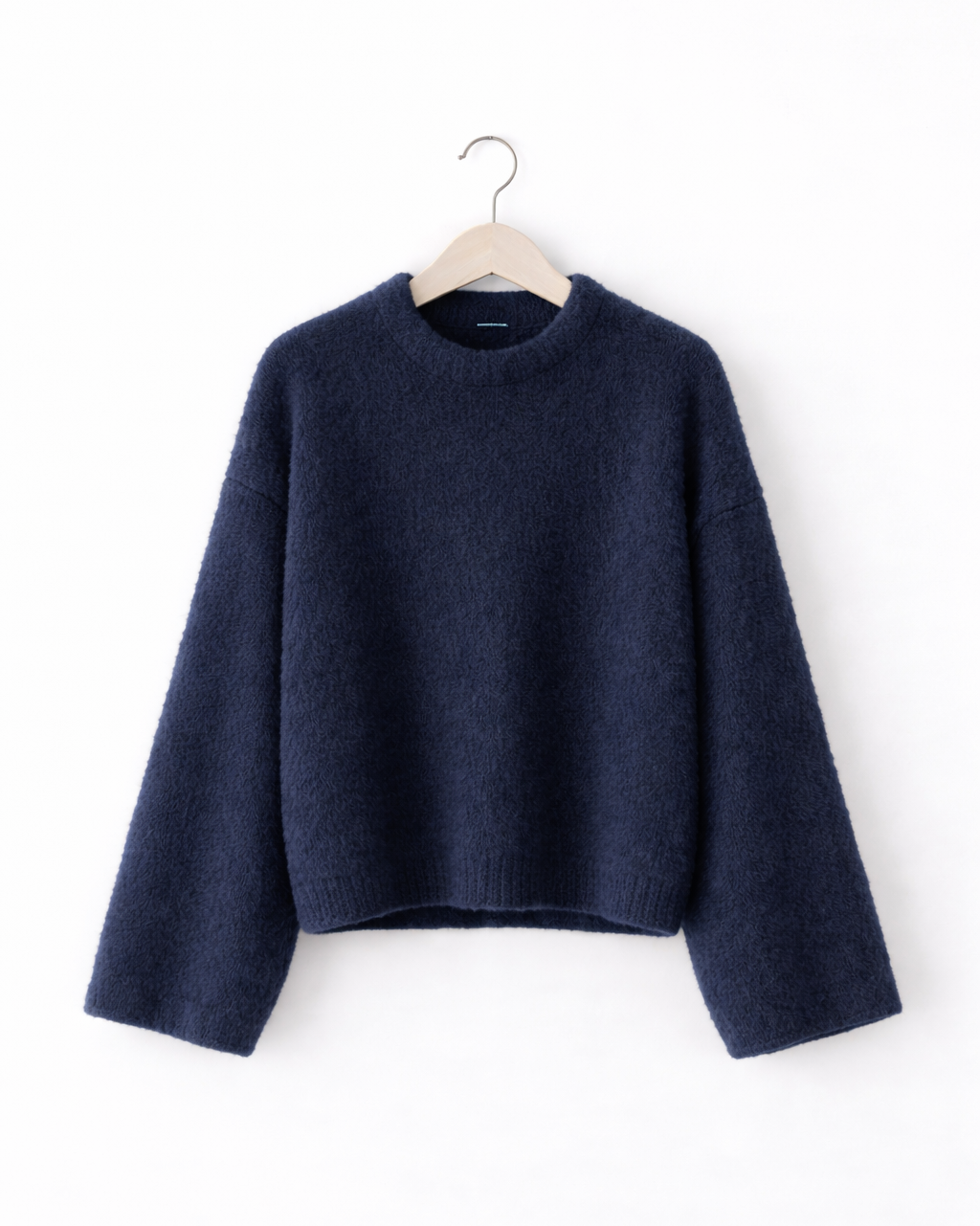 Navy blue sweater on a hanger against a white background