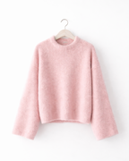 Pink sweater on a hanger against a white background