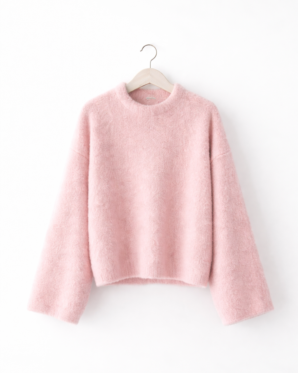 Pink sweater on a hanger against a white background