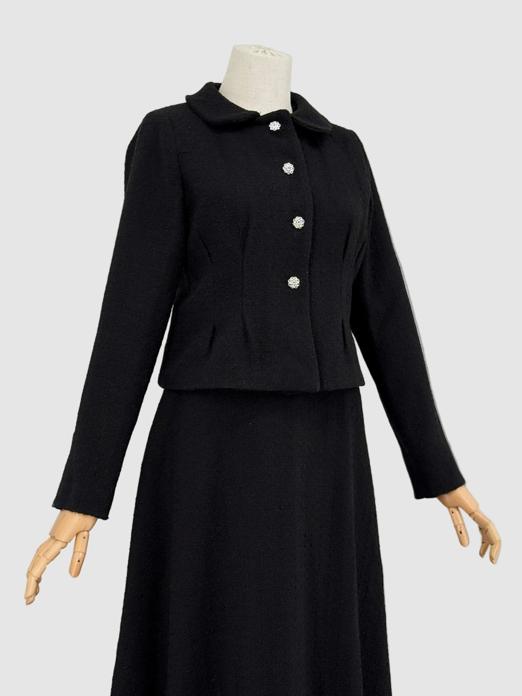 black tweed suit on a mannequin against a plain background