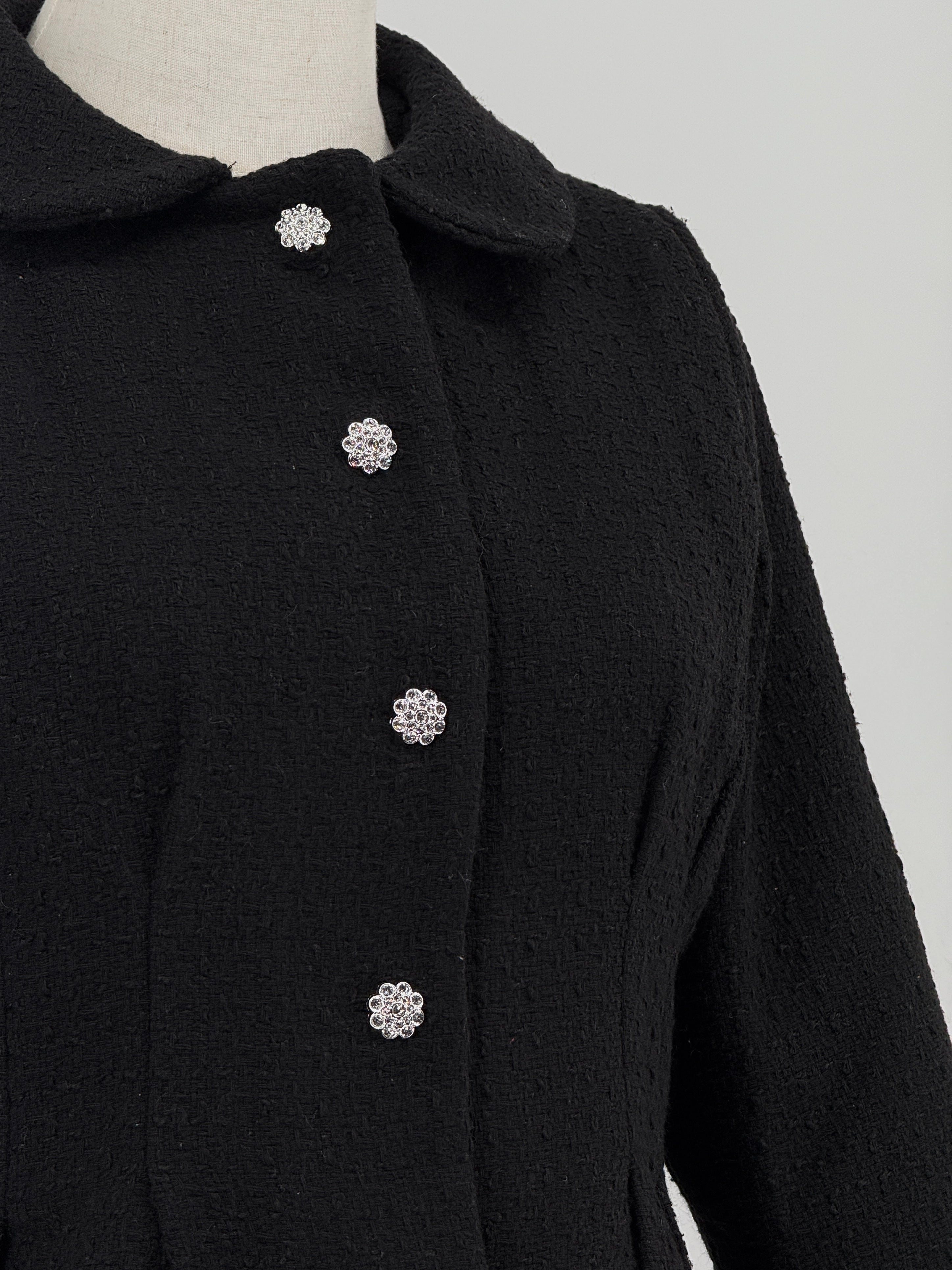 close-up of a black tweed suit on a mannequin against a plain background