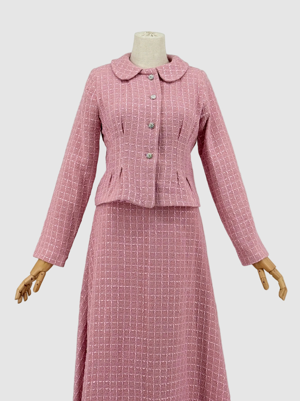 Pink tweed suit on a mannequin against a plain background
