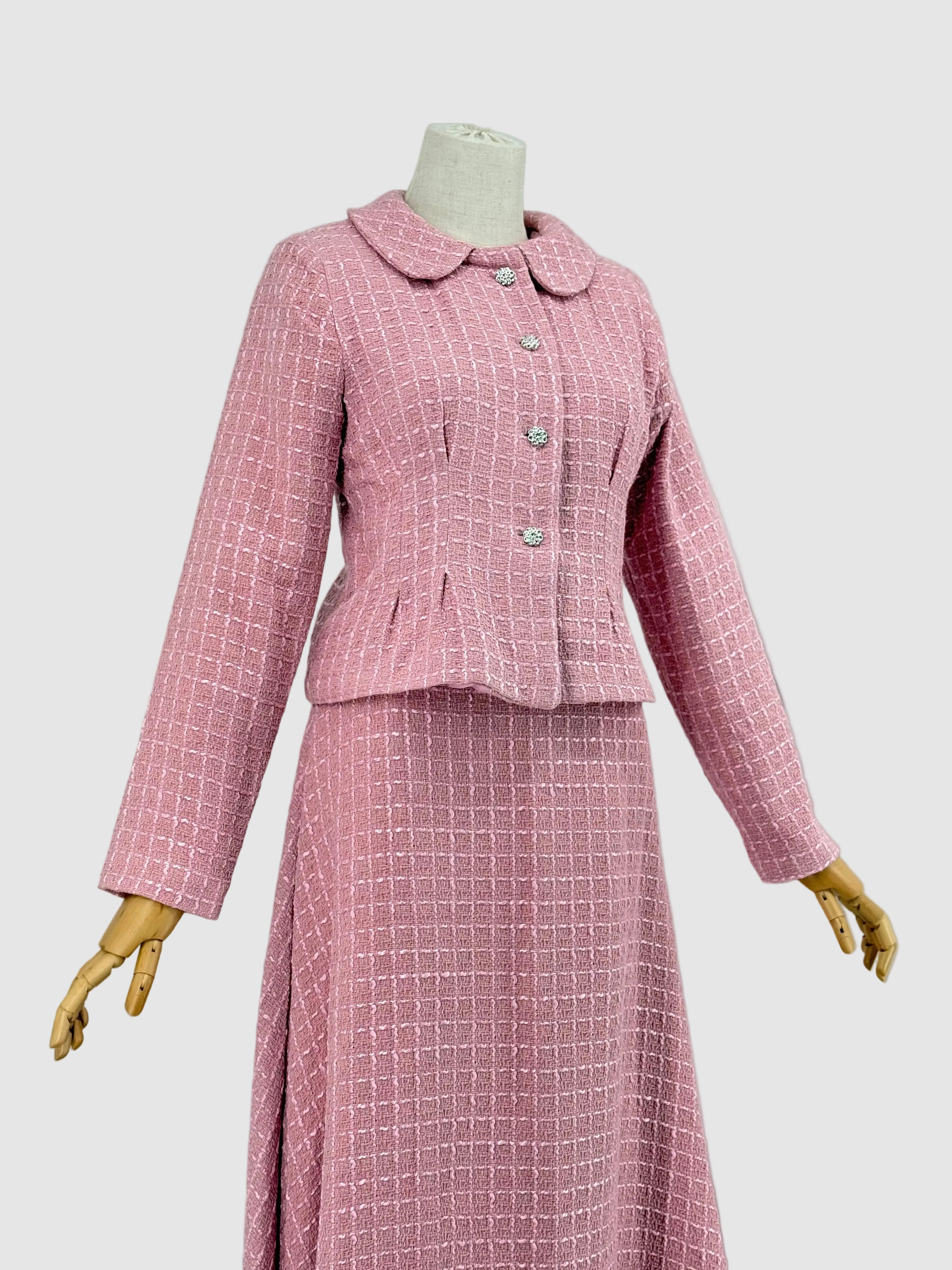 Pink tweed suit on a mannequin against a plain background
