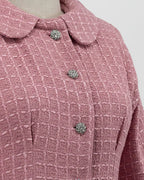 close-up of a pink tweed suit on a mannequin against a plain background