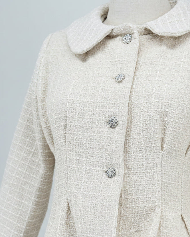 close-up of an off-white tweed suit on a mannequin against a plain background