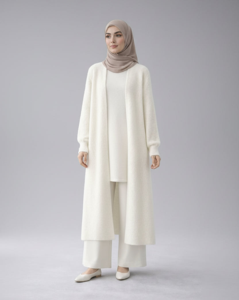 Woman wearing a white cardigan with a beige hijab in a minimalistic setting