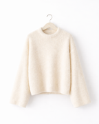 off-white sweater on a hanger against a white background