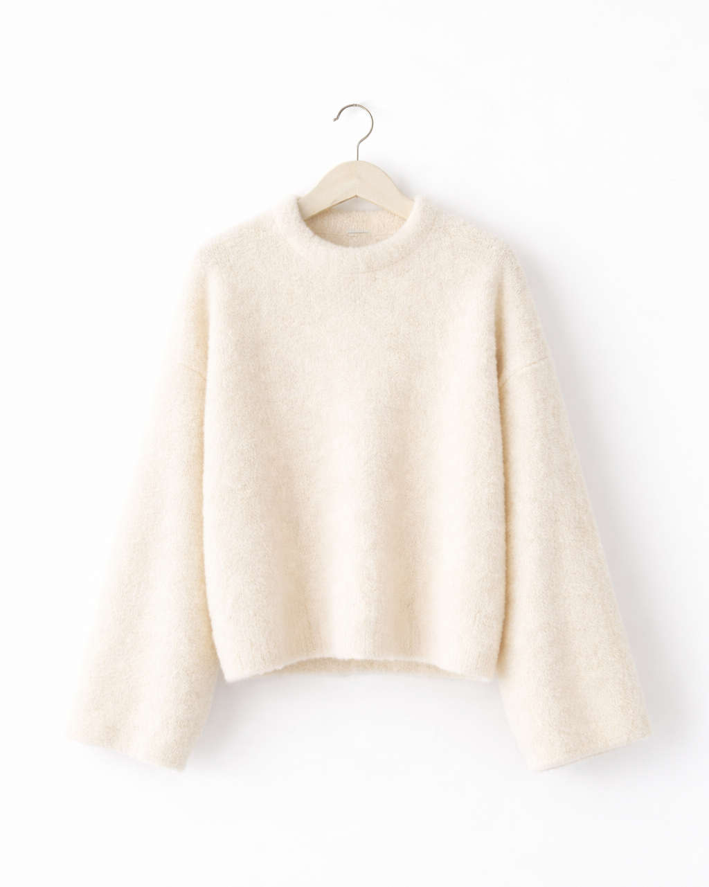 off-white sweater on a hanger against a white background